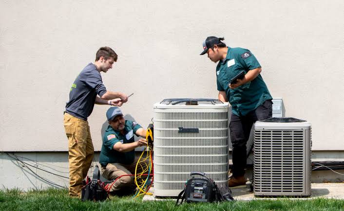 A team inspecting outdoor residential cooling systems