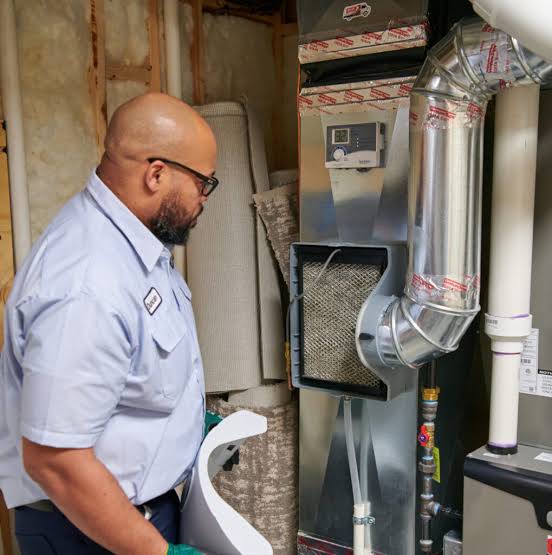 Technician inspecting an indoor furnace and metal duct connections