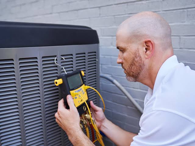 Technician using a digital diagnostic gauge to inspect an air conditioner